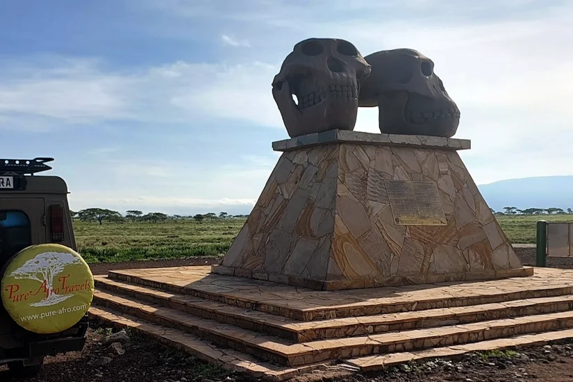 Pure Afro Travels safari vehicle parked by the historic Zinj monument at Olduvai Gorge, introducing our team and about us page.